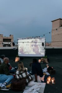Enjoying a cozy movie night on a rooftop with friends and ambient lights.
